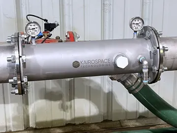 Stainless injector mounted horizontally inside a pump house with a gauge at each flange