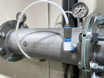 Close-up of an injector with a white oxygen feed line entering through a compression fitting
