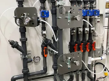 Inline injectors fitted to an existing PVC irrigation manifold with pressure gauges and zone valves