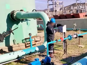 Operator adjusting a control panel beside the injection line at a tank battery