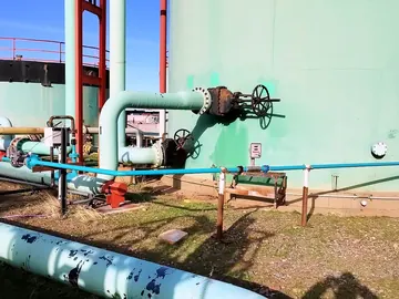 Blue injection line running along the base of a storage tank and tying into the process piping