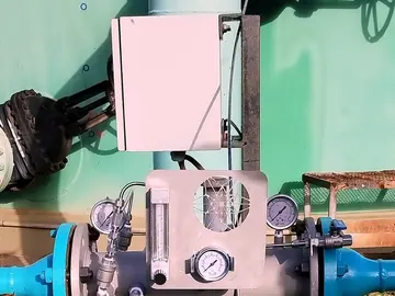 Control enclosure and flow meter mounted above an injector in the line at the base of a storage tank