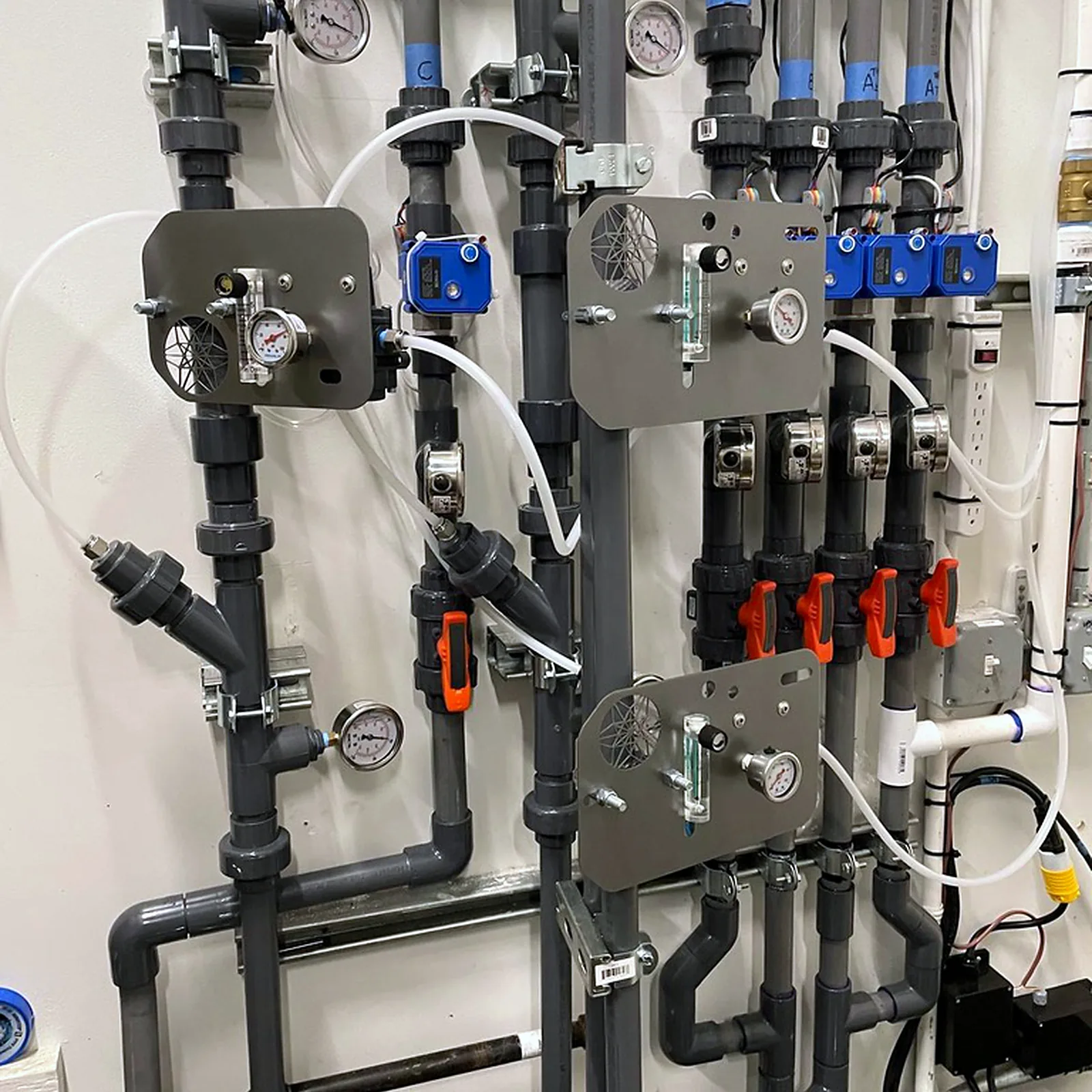 Inline injectors fitted to an existing PVC irrigation manifold with pressure gauges and zone valves