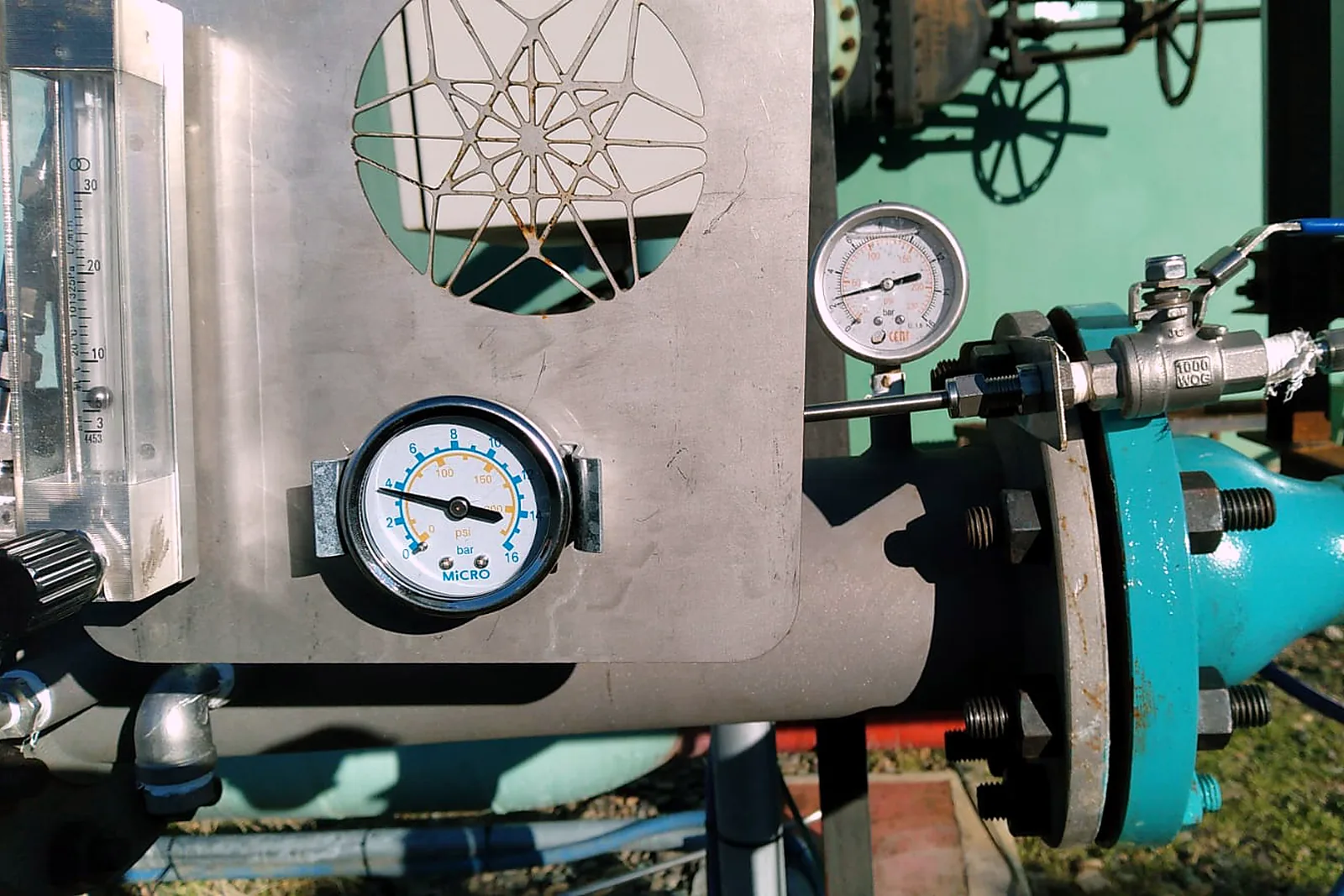 Stainless metering panel carrying a rotameter and pressure gauges, mounted beside the injector flange on the injection line